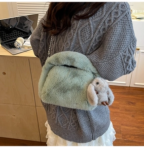 Close-up of fluffy green plush handbag with metal chain and cute rabbit charm detail