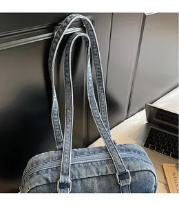 Detail view of the durable blue denim shoulder bag with silver rings and long straps
