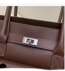 Macro view of silver Kelly buckle hardware on high-quality dark brown leather tote bag