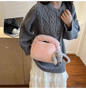 Close-up of pink fluffy plush bag with a cute rabbit pendant and metal chain strap