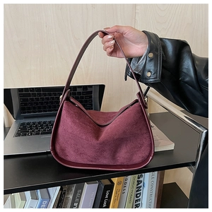 Détail du sac bandoulière bordeaux en daim montrant la texture mate et la courbe en V