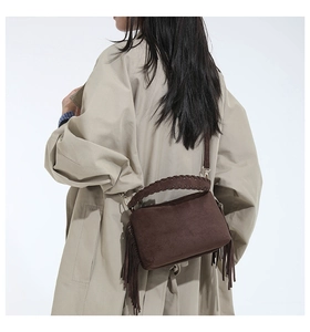 Detail of dark coffee suede shoulder bag with long side fringes and woven handle