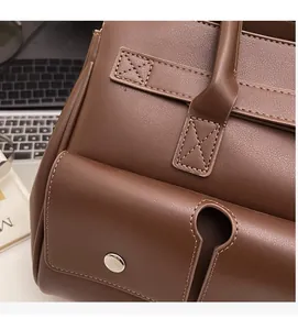 Detail of brown leather tote showing silver metal buckle and reinforced cross stitching