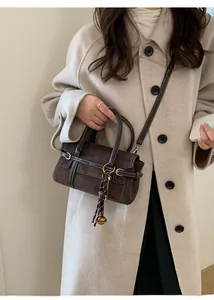 Detail of chocolate vintage suede Boston bag with leather trim and tassel pendant