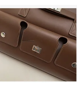 Detail of a brown leather shoulder bag featuring a silver metal twist lock and texture