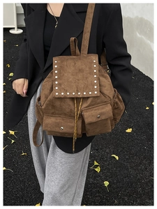 Détail du sac à dos rétro en daim marron avec rivets argentés et cordons jaunes