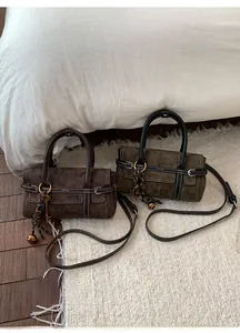 Detail of vintage suede crossbody bags with contrast stitching and decorative metal charms