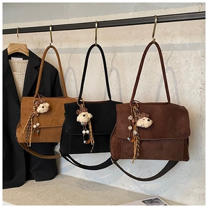 Suede tote bags in camel, black, and dark brown with plush bear charms and tassels