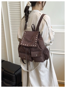 Détail du sac à dos vintage en daim marron foncé avec rivets et fermeture à cordon
