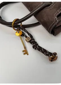 Detailed macro view of retro brass keychain with woven cord on vintage leather handle
