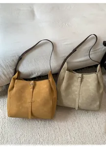 Two large suede tote bags in ginger and beige with leather straps on a white bed