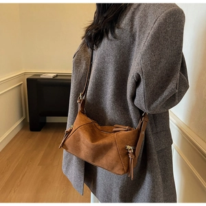 Detail of brown suede shoulder bag with side zipper and stylish long tassel decorative puller