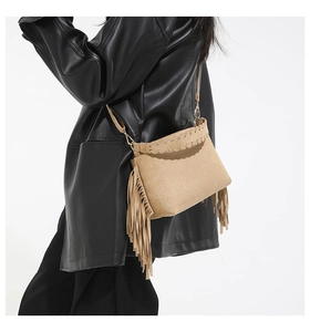 Detail of suede crossbody bag featuring long fringe tassels and braided edge trim