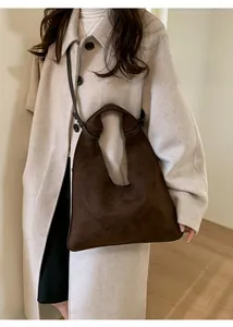 Detail of a dark coffee suede tote bag with a unique leather knot handle and shoulder strap