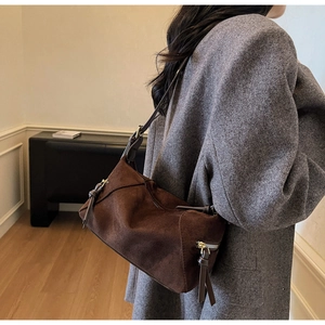 Detailed macro view of dark brown suede shoulder bag featuring a premium metal side zipper