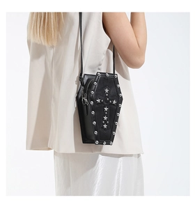 Detailed shot of coffin crossbody bag with silver cross, star studs and heart pendant