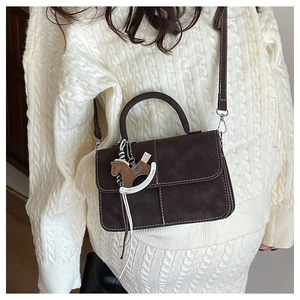Detail of vintage brown tote with stitching, horse charm, and detachable strap