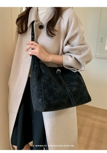 Détail du sac cabas rétro noir avec boucle argentée sur un manteau en laine