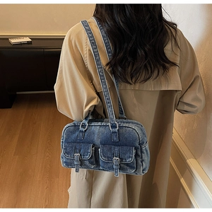 Detail of washed denim shoulder bag with dual flap pockets and silver buckles