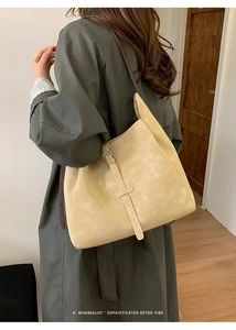 Détail du grand sac cabas rétro beige avec sangle à boucle sur un manteau vert