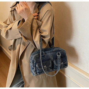 Detail of blue denim pillow bag with silver buckles worn with a stylish trench coat