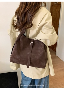 Détail d'un sac cabas marron en daim avec boucle rétro dans un décor minimaliste