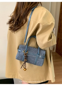 Detailed side view of a gray-blue retro handbag with woven pendant and leather handle