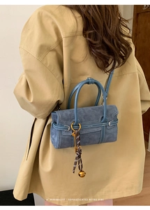 Detail of blue matte retro crossbody bag with decorative key charm and bell pendant