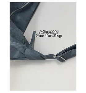 Detail of adjustable shoulder strap with silver buckle on blue suede dumpling bag