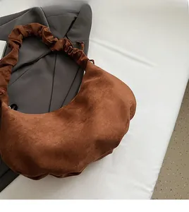 Detail view of brown faux suede hobo bag featuring a pleated handle and drawstring design