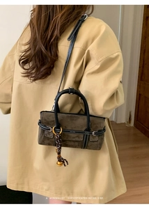 Detail of olive suede crossbody bag featuring white contrast stitching and silk scarf charm