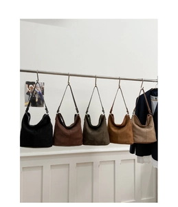Five suede tote bags in various colors hanging on a rack for a fashion product display