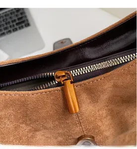 Detail of vintage brown suede bag showing smooth bronze zipper and leather lining texture