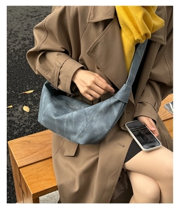 Detail of grey-blue hobo bag featuring vintage-style leather texture and knotted strap