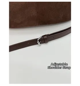 Detail of adjustable smooth leather strap and silver buckle on brown suede tote bag