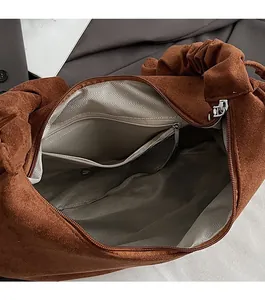 Interior of dark brown suede tote bag featuring grey herringbone lining and zipper pocket