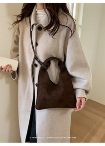 Deep brown suede handbag styled with a coat for a minimalist sophisticated retro vibe
