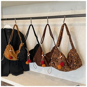 Hobo bags in assorted colors featuring decorative pom poms and wide shoulder straps