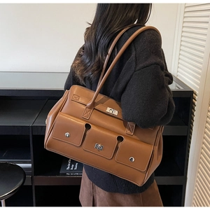 Detail view of brown leather tote bag showing multi-pockets and metal twist lock