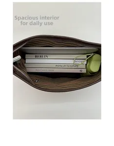 Spacious interior of dark brown suede tote bag holding books and a folding umbrella