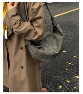 Outdoor side view of a dark grey crescent shoulder bag with white double stitching detail