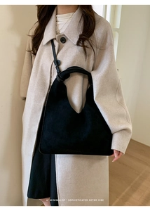 Bolso hobo retro negro mate con detalle de nudo mostrado en modelo con abrigo