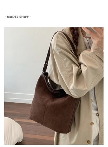 Close-up of a vintage dark brown suede bucket bag worn with a classic khaki trench coat