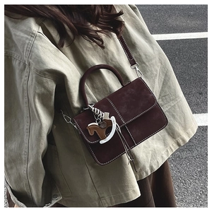 Detailed close-up of retro brown suede handbag featuring elegant white contrast stitching