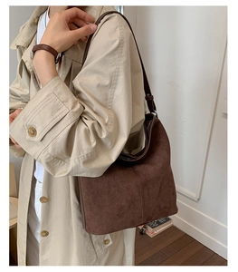Macro detail of dark brown faux suede tote bag with elegant shoulder strap and stitching