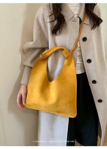 Close-up of a mustard yellow suede tote bag featuring a creative knotted handle design