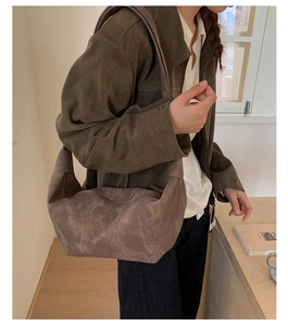 Detail of minimalist dark brown suede crescent shoulder bag with smooth zipper closure