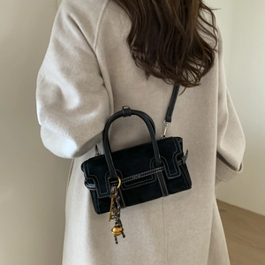 Retro black matte crossbody bag with white stitching and gold charms on model