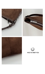 Detailed macro view of silver zippers and reinforced stitching on brown suede bucket bag