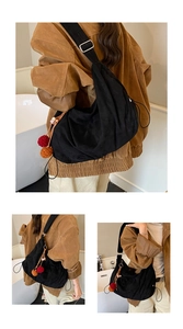 Detail of black suede hobo bag with colorful pompom charms and adjustable silver buckle
